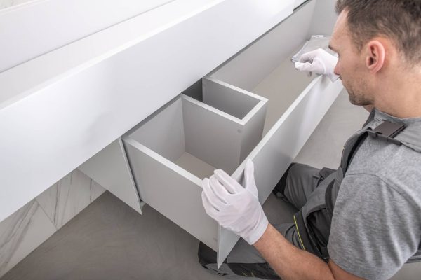 professional in gray shirt and white gloves installing storage system